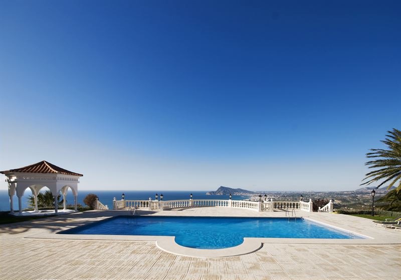 Stor terrass med swimmingpool med utsikt över havet. Foto: Fastighetsbyrån 