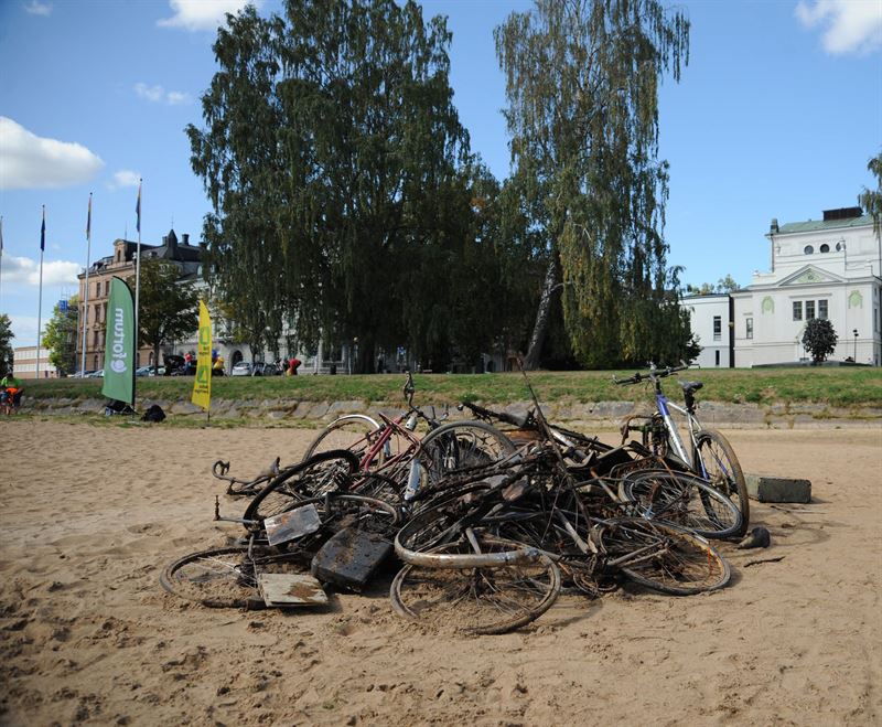 En hög med cyklar på en sandstrand. Vid Klarälven i Karlstad. Foto: Fortum