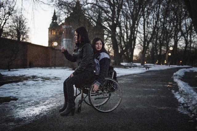Flicka sitter i knäet på en flicka i rullstol. Foto: Anna Tärnhuvud. Titel: Felicia